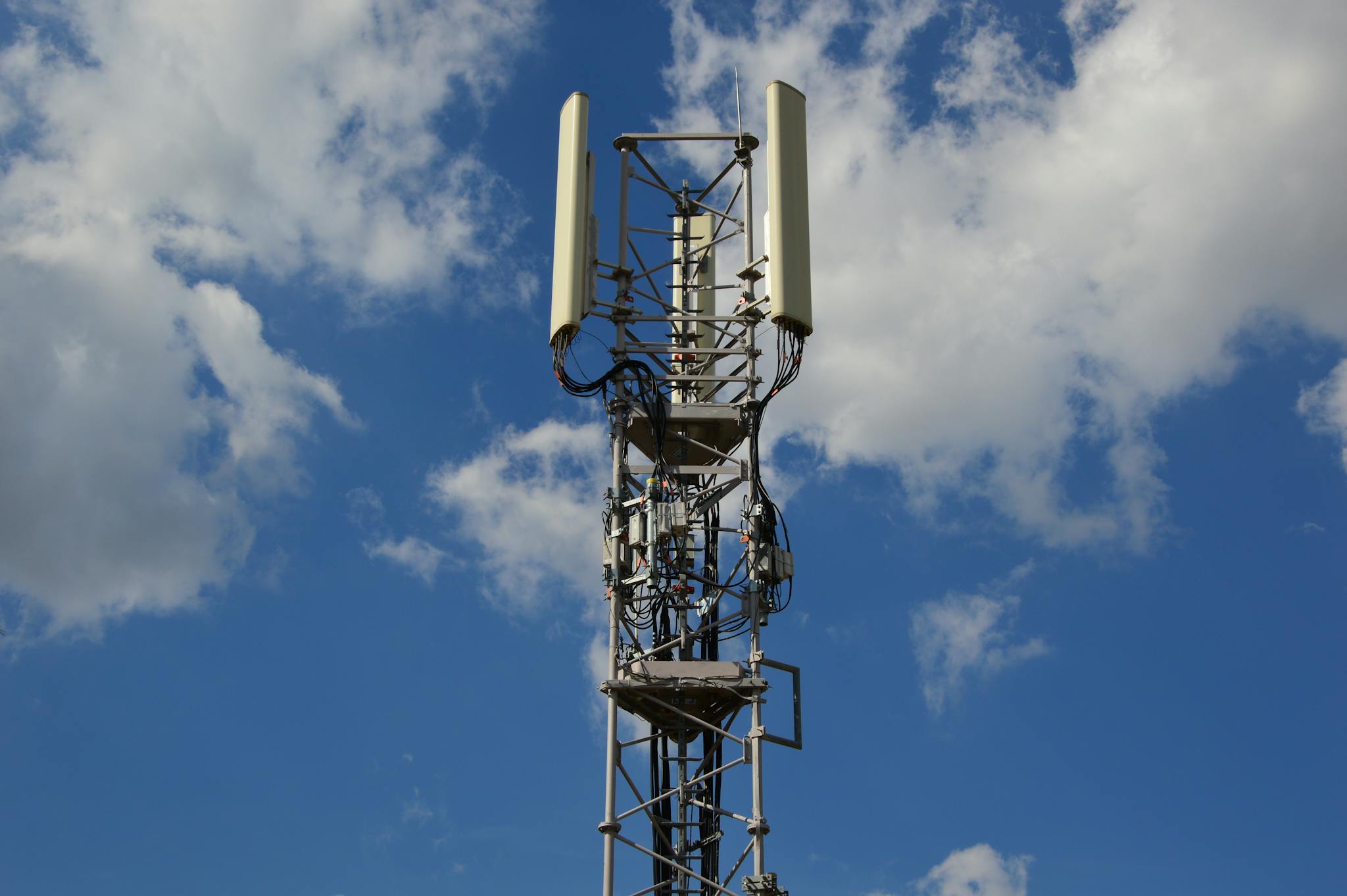 A tall cellular communication tower against a vivid blue sky, symbolizing modern technology.